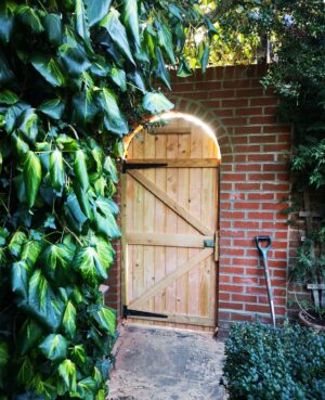 beautiful wooden arched gate in a brick wall