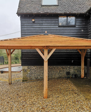 light wood square car port next to black converted barn