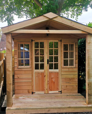 brown wood summer house with glass Georgian style windows and doors